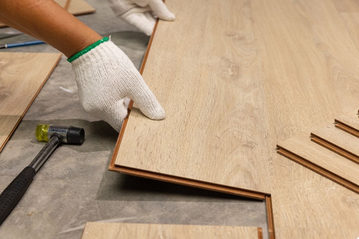 A person installing wood flooring, carefully laying down planks on a clean, prepared surface.