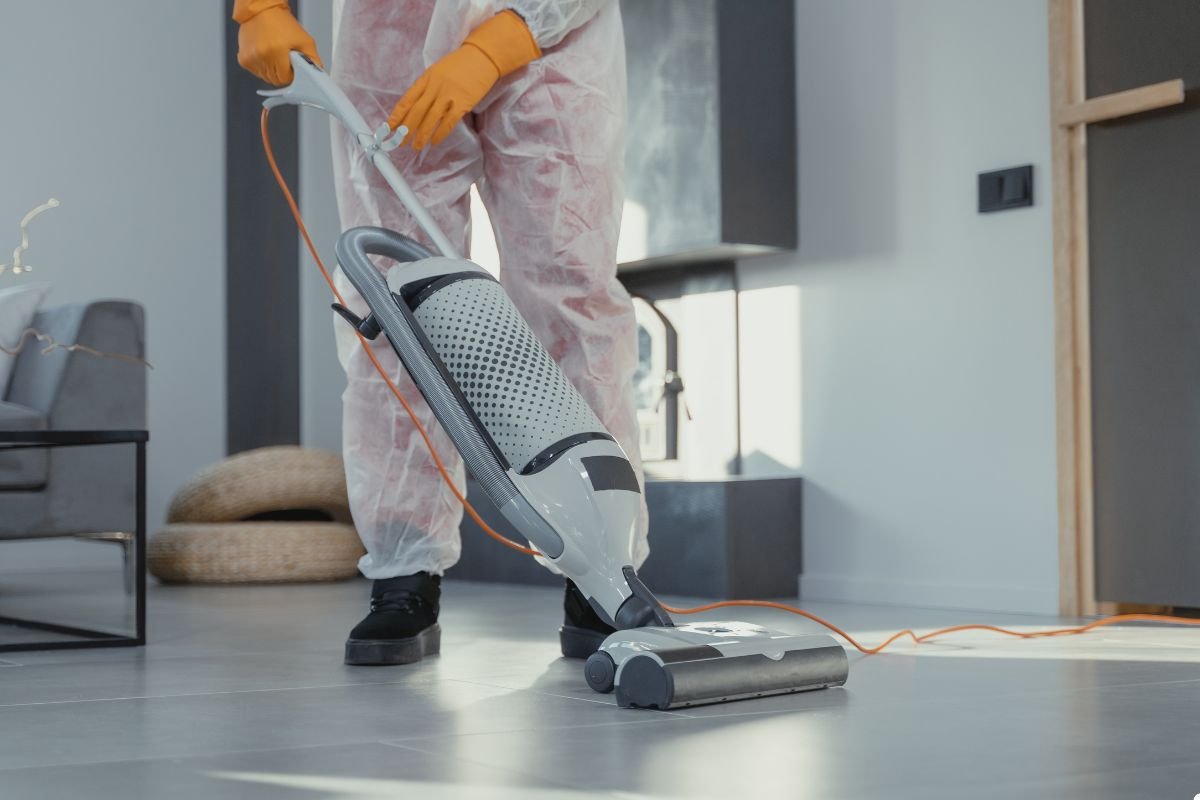 An individual wearing a protective suit is engaged in cleaning a room, emphasizing safety and hygiene.