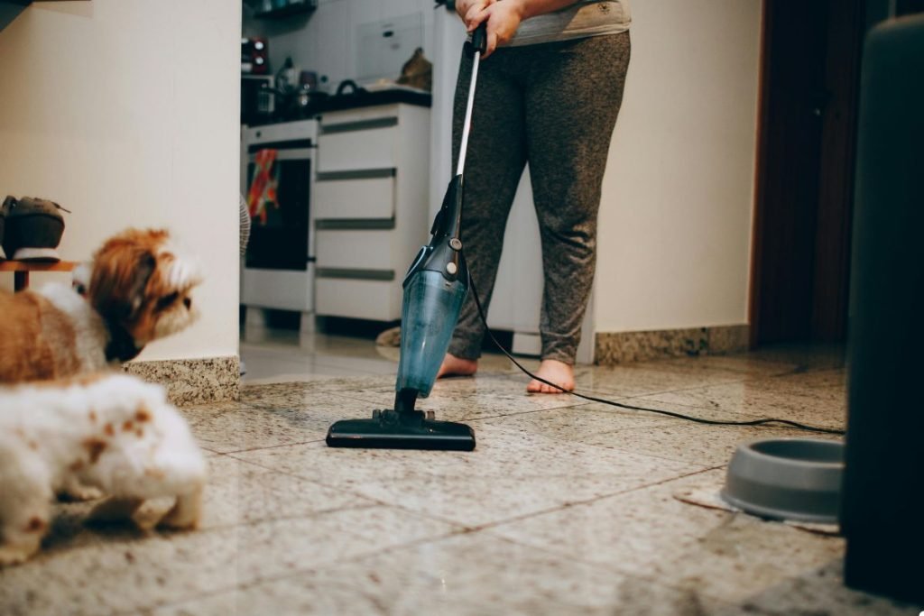 A woman using a vacuum cleaner to clean the floor in a tidy indoor space.