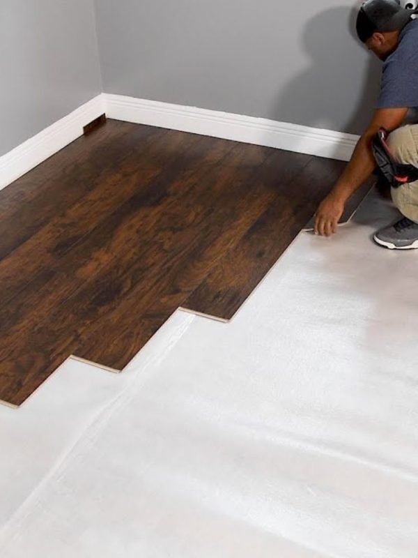 A man works on installing wood flooring in a room, highlighting flooring services in San Jose, CA.