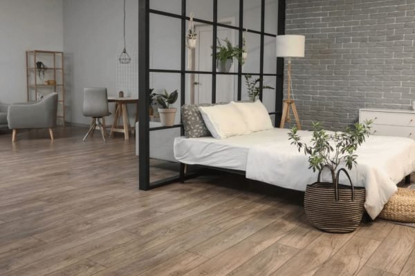 A well-furnished bedroom with a bed, table, and window, highlighting laminate flooring services in San Jose, CA.